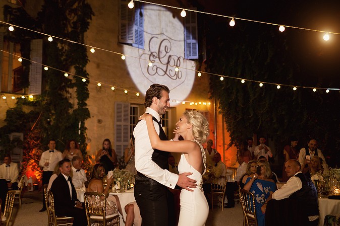 Couple dancing at a wedding under lighting and a logo projection